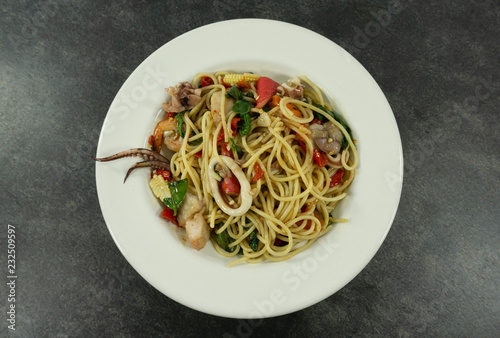 Spaghetti seafood in a white dish on a black stone floor table.Top view with copy space.