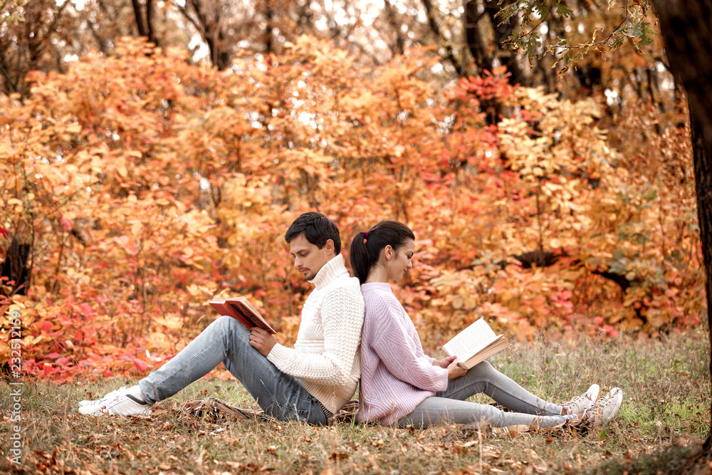 couple in love sitting in autumn park and reading book couple in love sitting in autumn park and reading book