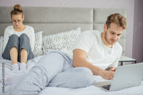 handsome fair-haired man surfing the Net while his wife reading e-book. technology concept. modern family. online cominication. non-vebal communication. virtual world photo