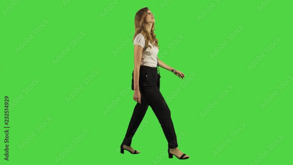 A young businesswoman walking and smiling while looking upwards in a full body shot over a green screen. A young businesswoman walking and smiling while looking upwards in a full body shot over a green screen.