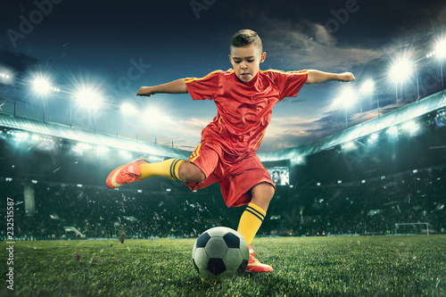 Young boy with soccer ball doing flying kick at stadium photo