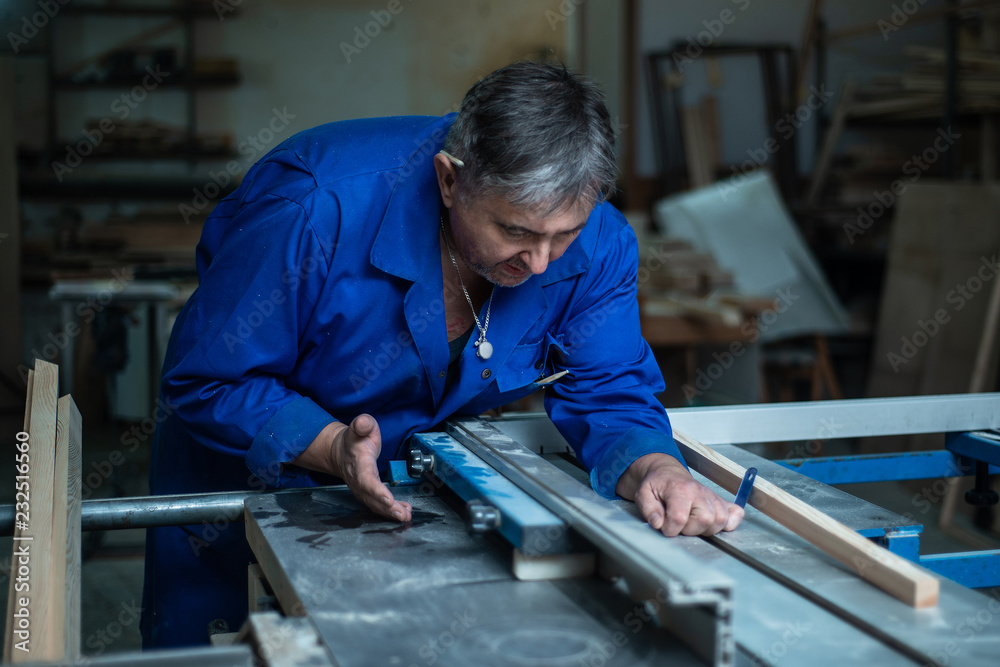 Carpenter at work at his workshop, wood processing on a woodworking machine Carpenter at work at his workshop, wood processing on a woodworking machine