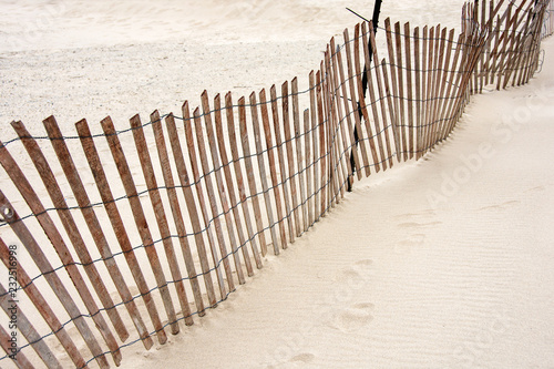 tilted weathered old wooden fence on beach sand