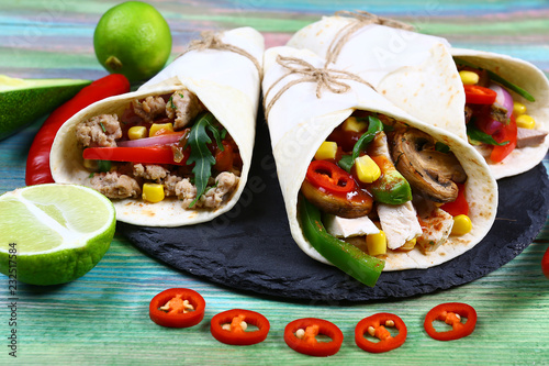 Mexican restaurant fast food - wrapped burritos with pork meat, mushrooms and vegetables closeup at wooden desk on table. Mexican burritos closeup photo