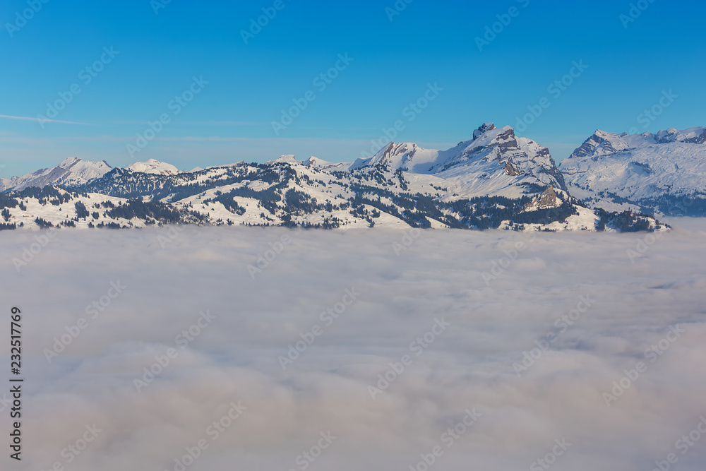 Summits of the Alps rising from sea of fog - a wintertime view from the Fronalpstock mountain in the Swiss canton of Schwyz