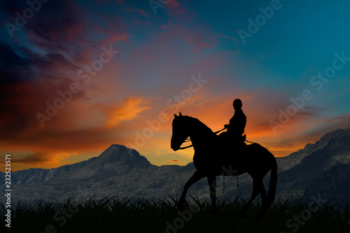 Sylwetka jeździec jedzie na koniu przy zmierzchem górami
