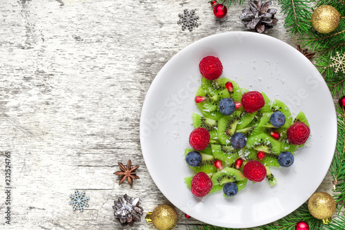 Funny edible christmas tree made from fruits and berries with fir tree and decorations. Christmas breakfast idea for kids