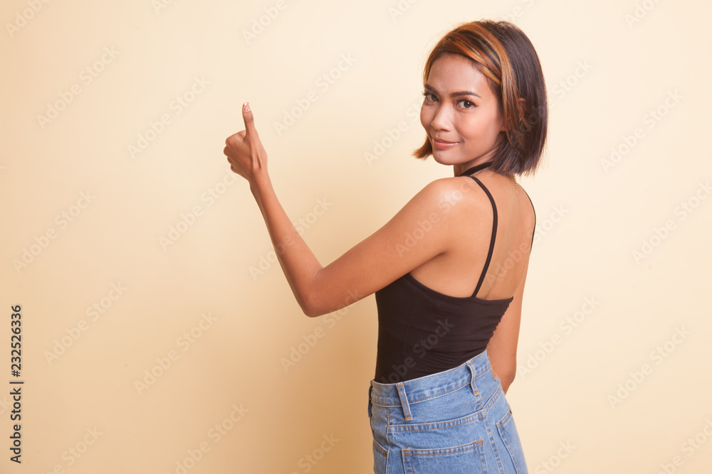 Young Asian woman turn back thumbs up. Young Asian woman turn back thumbs up.