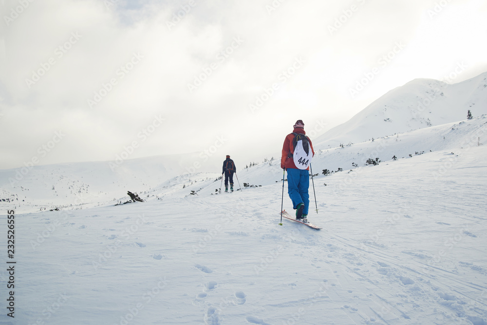 Ski touring couple hiking up a summit in the winter mountains