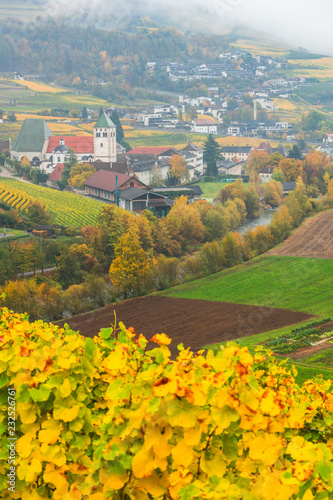 Picturesque autumnal view on Novacella, Varna, Bolzano in South Tyrol. Mountain scenery in Northern Italy. View from the top on the mountain valley. Colourful vineyards and yellow foliage on trees.