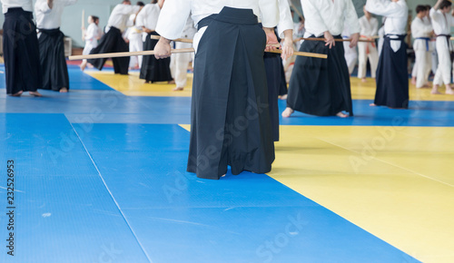 People in kimono practice Aikido with wooden jo on martial arts weapon training seminar
