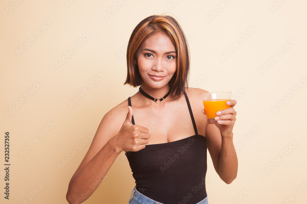 Young Asian woman thumbs up drink orange juice. Young Asian woman thumbs up drink orange juice.