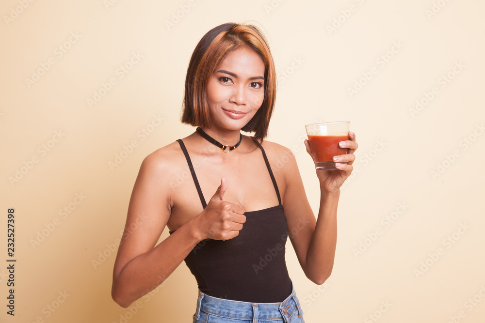 Young Asian woman thumbs up with tomato juice. Young Asian woman thumbs up with tomato juice.
