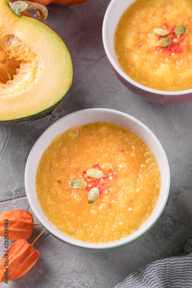 Autumn soup pumpkin puree in ceramic cups on a gray background top view. Autumn soup pumpkin puree in ceramic cups on a gray background top view.
