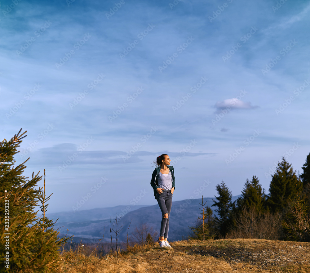 young woman standing on mountain ridge and enjoy the view at sunset