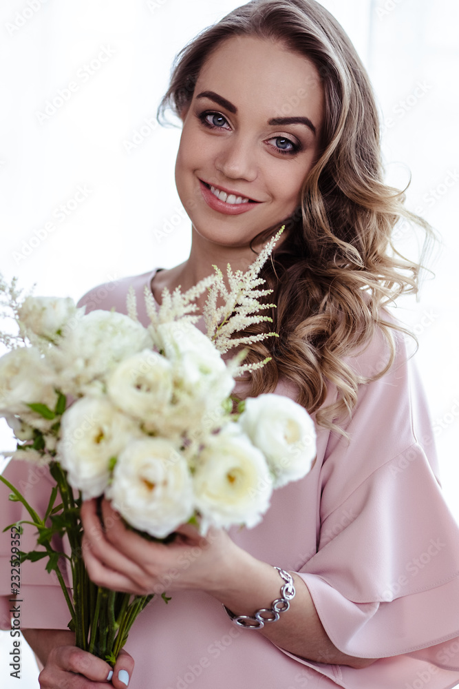 Beautiful young blonde woman with bouquet of white flowers. Portrait of pretty blonde girl in pink clothes. Florist in her work place Beautiful young blonde woman with bouquet of white flowers. Portrait of pretty blonde girl in pink clothes. Florist in her work place