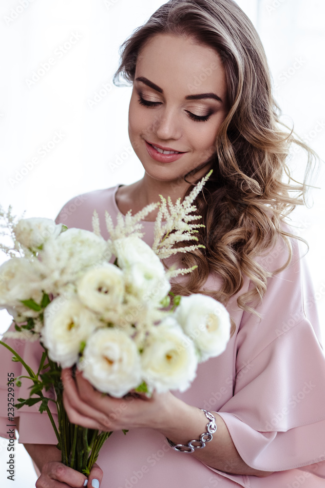 Beautiful young blonde woman with bouquet of white flowers. Portrait of pretty blonde girl in pink clothes. Florist in her work place Beautiful young blonde woman with bouquet of white flowers. Portrait of pretty blonde girl in pink clothes. Florist in her work place