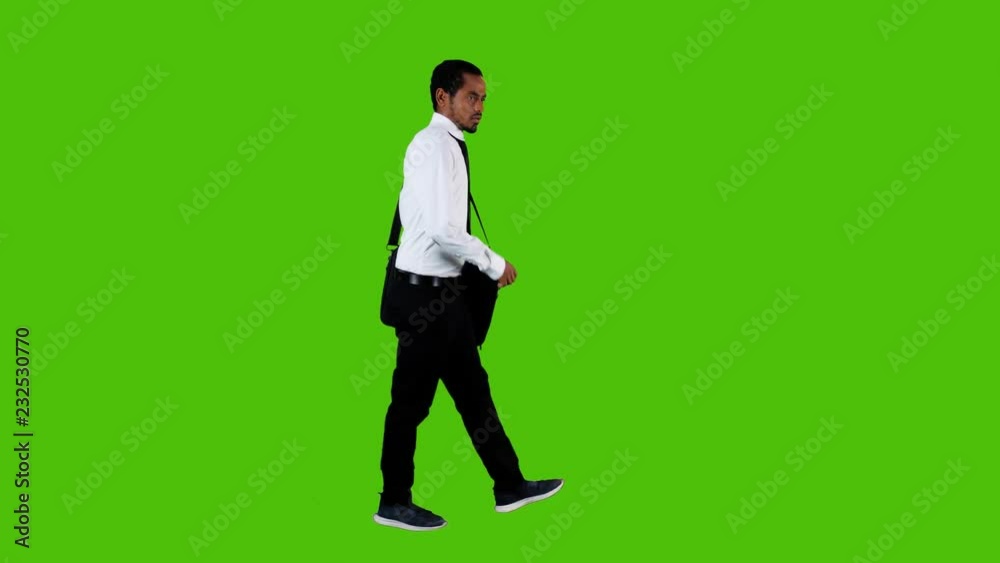 Sad ill and depressed businessman walking upset over a green background. Side long shot. Sad ill and depressed businessman walking upset over a green background. Side long shot.