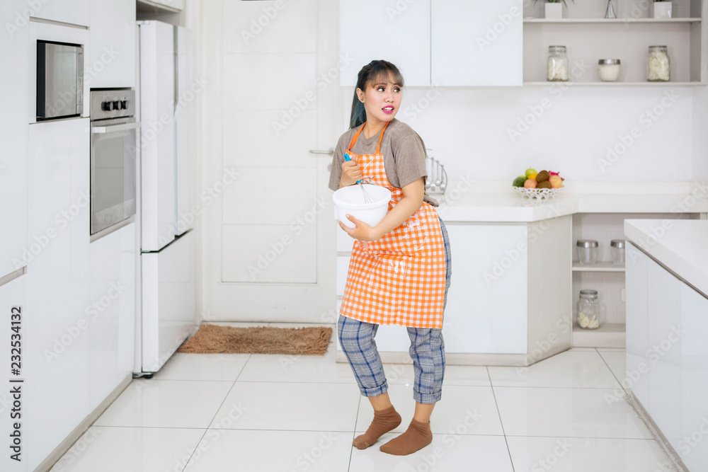 Young housewife mixing dough in the kitchen Young housewife mixing dough in the kitchen