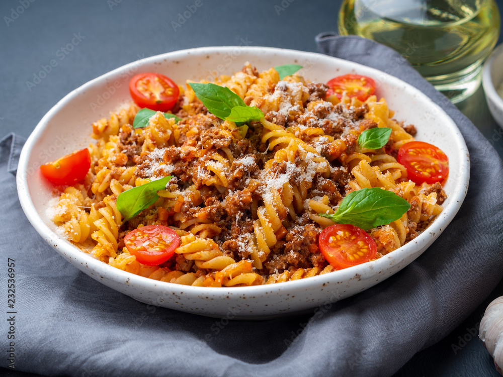 Bolognese pasta. Fusilli with tomato sauce, ground minced beef, basil leaves. Traditional italian cuisine. Side view Bolognese pasta. Fusilli with tomato sauce, ground minced beef, basil leaves. Traditional italian cuisine. Side view