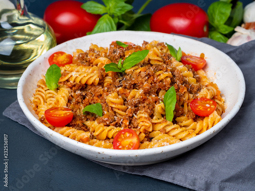 Bolognese pasta. Fusilli with tomato sauce, ground minced beef, basil leaves. Traditional italian cuisine. Side view
