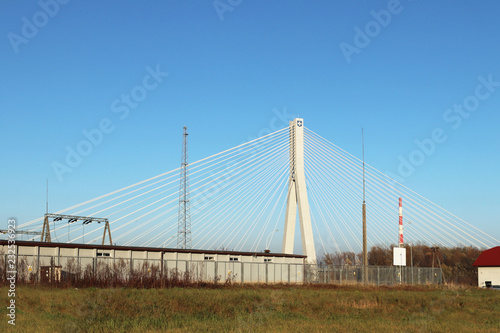 Rzeszow, Poland - 9 9 2018: Suspended road bridge across the Wislok River. Metal construction technological structure. Modern architecture. A white cross on a blue background is a symbol of the city. © Xato Lux