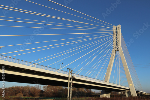 Rzeszow, Poland - 9 9 2018: Suspended road bridge across the Wislok River. Metal construction technological structure. Modern architecture. A white cross on a blue background is a symbol of the city.