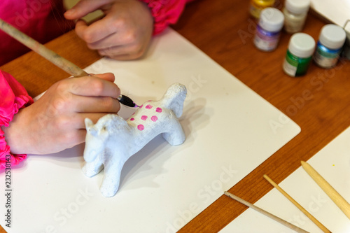 the child painting  the handmade horse with paint brushes