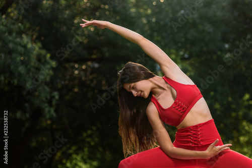 Flexible woman practicing morning yoga in summer park