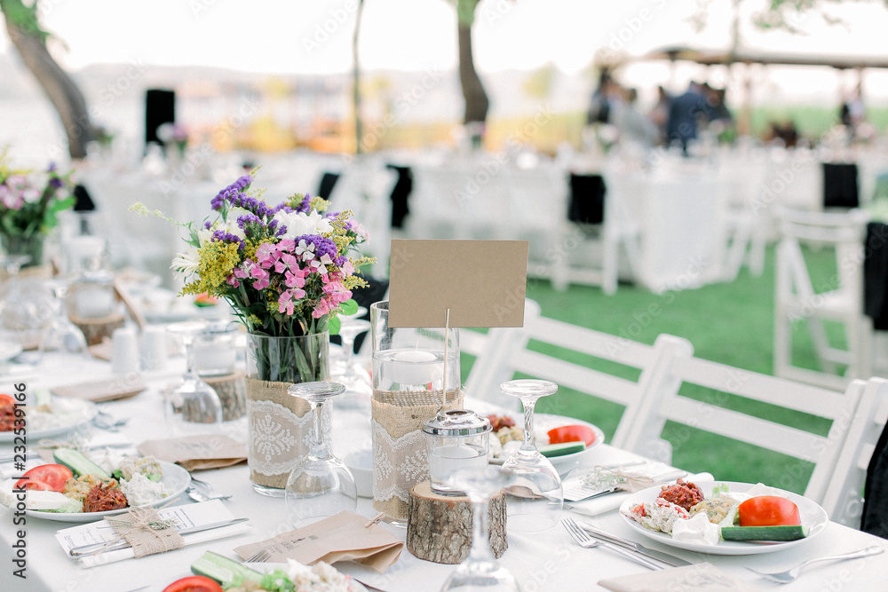 Rows of empty white folding chairs sitting on a lawn. Table setup Rows of empty white folding chairs sitting on a lawn. Table setup