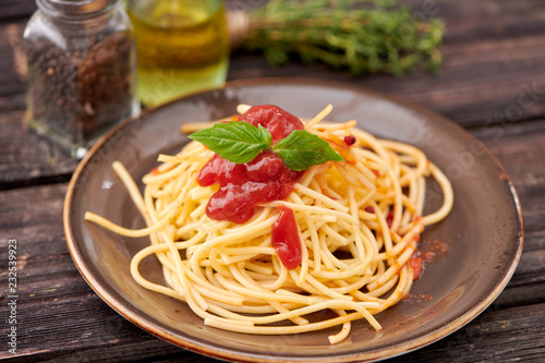 spaghetti with ketchup and Basil on dark wooden background