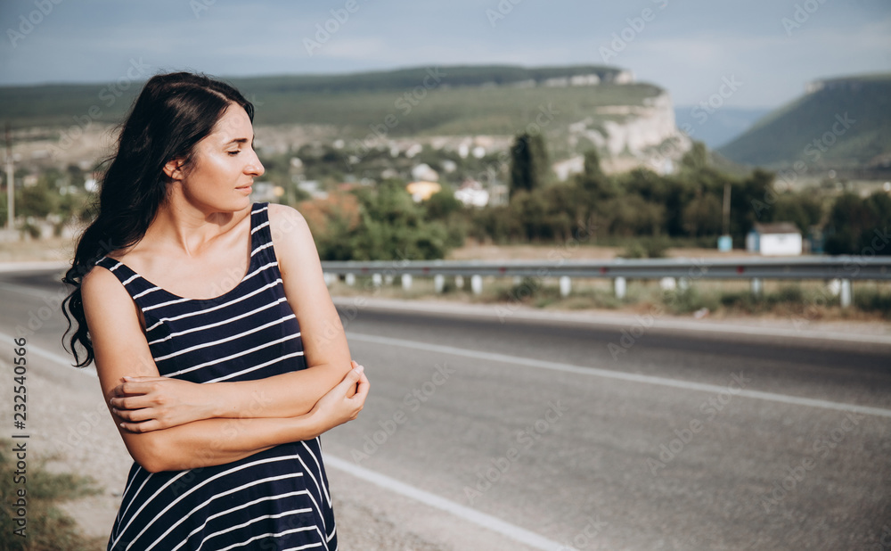 Fototapeta premium Woman on the road at beautiful background of nature and mountains