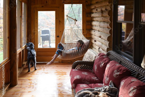 little boy hanging out in hammock in the porch of a cabin