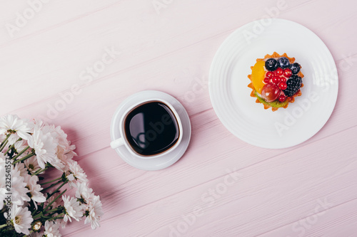Composition of delicious small berry cupcake, espresso and fresh flowers