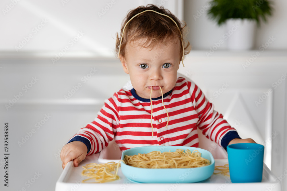 Baby making funny face while eating spaghetti noodles Baby making funny face while eating spaghetti noodles