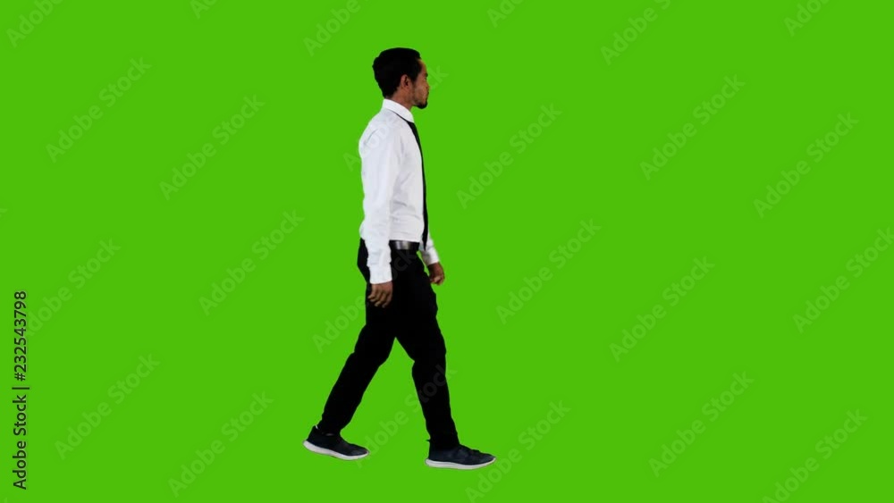 Happy young businessman walking and looking around over a green background. Full side shot. Happy young businessman walking and looking around over a green background. Full side shot.