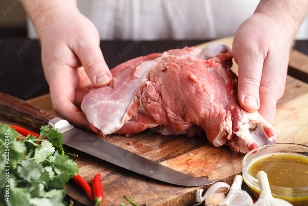 Strong professional man's hands cutting raw lamb meat, selective focus, close-up