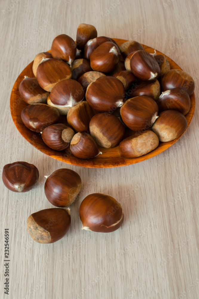 Ripe chestnuts on a plate on wooden background Ripe chestnuts on a plate on wooden background