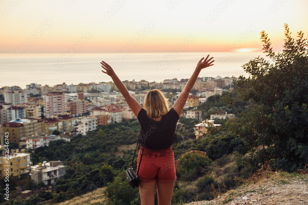 Hiker woman standing with hands up achieving the top. Girl welcomes a sunset. Tourism concept of Alanya, Turkey Hiker woman standing with hands up achieving the top. Girl welcomes a sunset. Tourism concept of Alanya, Turkey