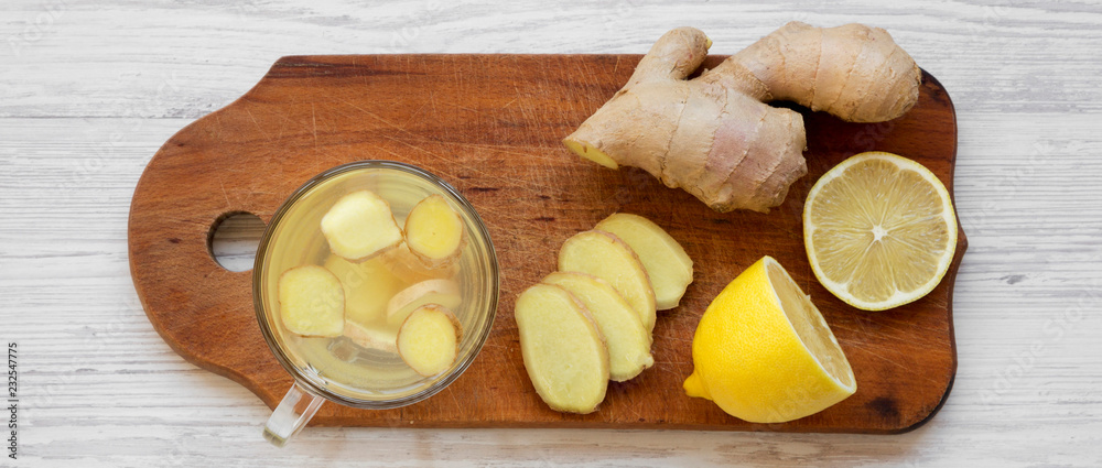 Homemade ginger tea with lemon on wooden board over white wooden background, overhead view. Flat lay, from above. Homemade ginger tea with lemon on wooden board over white wooden background, overhead view. Flat lay, from above.
