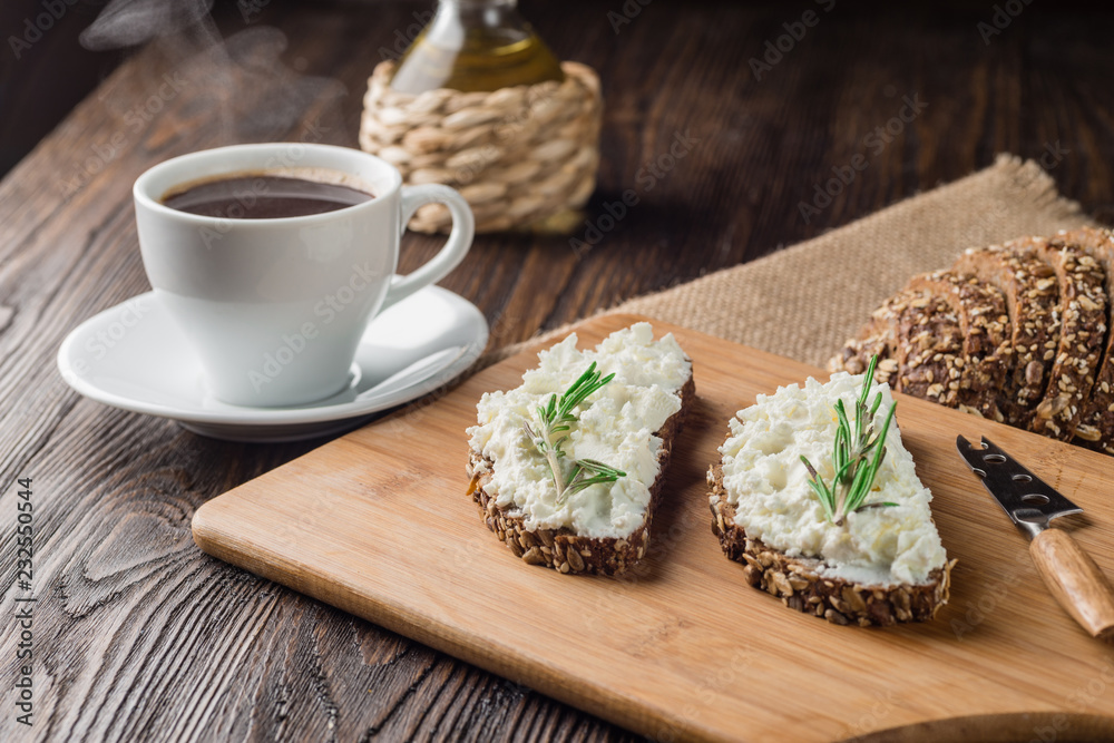 Breakfast with homemade sandwiches with cream-cheese and coffee on a wooden table.