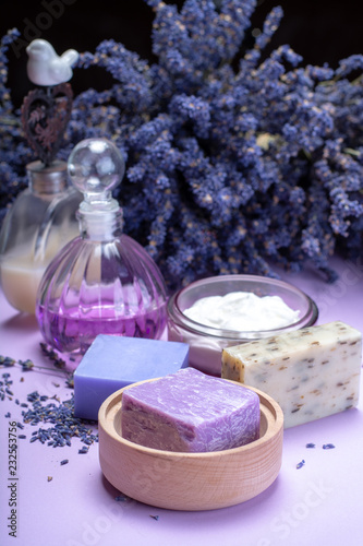 Natural healthy aromatherapy and skin treatment with organic French lavender  lavender soap  face cream  essential oils on purple background with dried lavender flowers