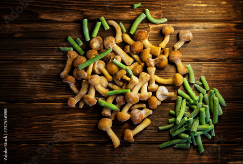 Frozen wild mushrooms and green beans on a wooden background with horizontal lines photo