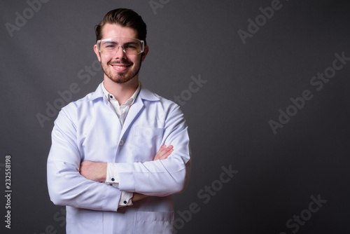 Young handsome bearded man doctor wearing protective glasses aga