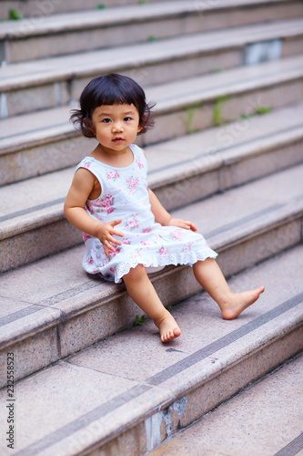 Chinese little girl sitting on steps looking at camera