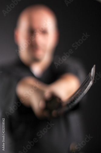 Samurai master training with sword in studio on black.