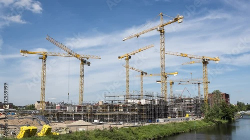 Many operating cranes at construction site, timelapse zoom in