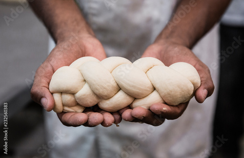 Raw challah bread dough in baker hands