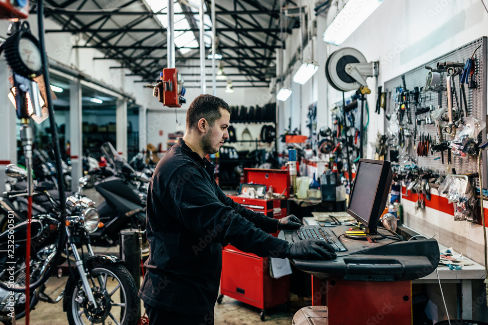Mechanic working in computer at the motorbike workshop Mechanic working in computer at the motorbike workshop