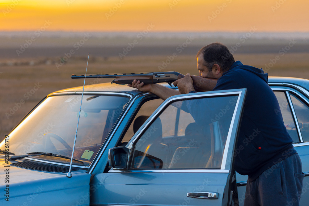 The guy shoots cartridges with a gun in nature, The hunter shoots at the target at sunset	